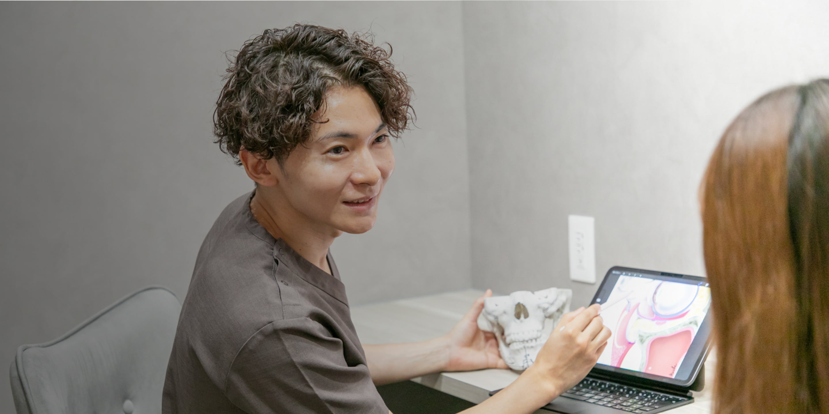 アビームクリニック院長前波芳周のカウンセリングの様子 タブレットと模型を用いながら患者さまに話している